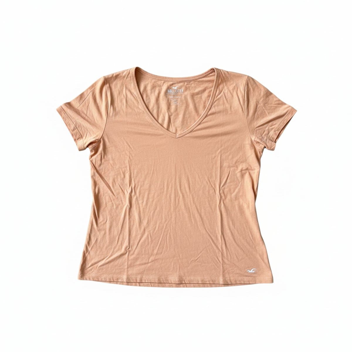 Women's Hollister peach-colored V-neck t-shirt, soft jersey fabric, minimalist style with small seagull logo, available at handpicked306 boutique.